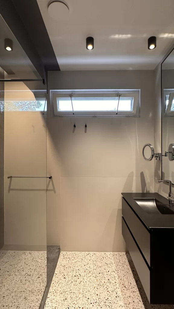 Salle de bain design à Garches avec porte invisible, carrelage grand format et robinetterie noire – DUstudiO Interiors
